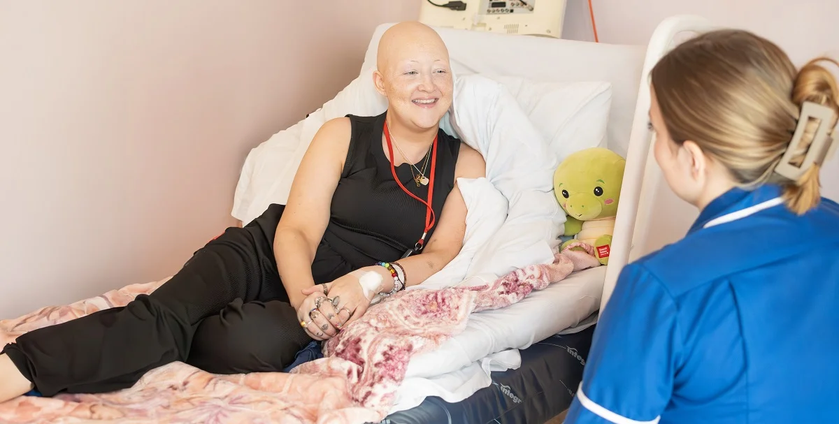 A Myton patient smiling in bed with a family member beside her